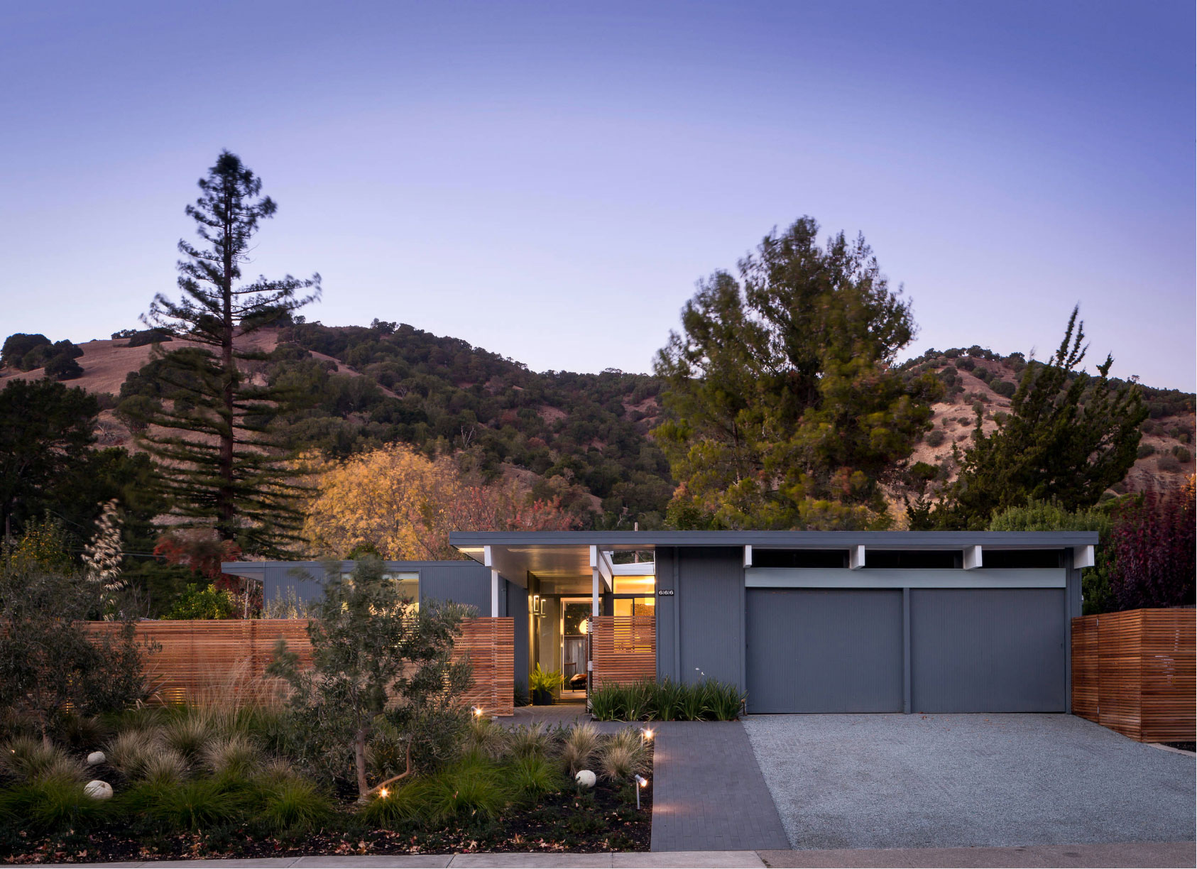 modern flat roof one-story home surrounded by trees and mountains in the background