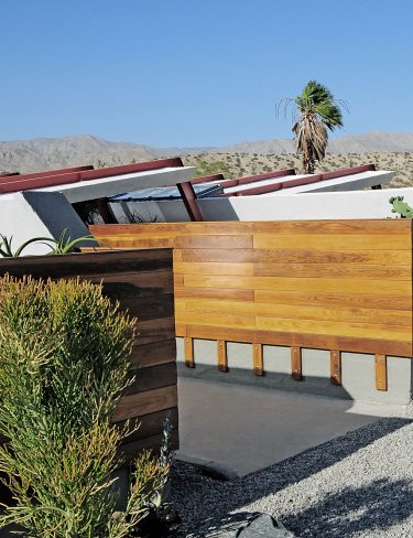 wood clad ranch style homes connected in a desert landscape and gravel drive