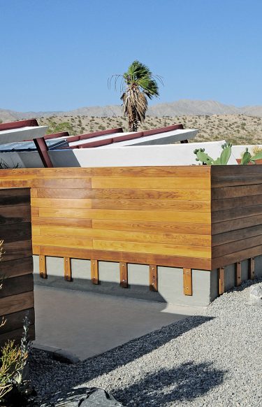 wood clad ranch style homes connected in a desert landscape and gravel drive