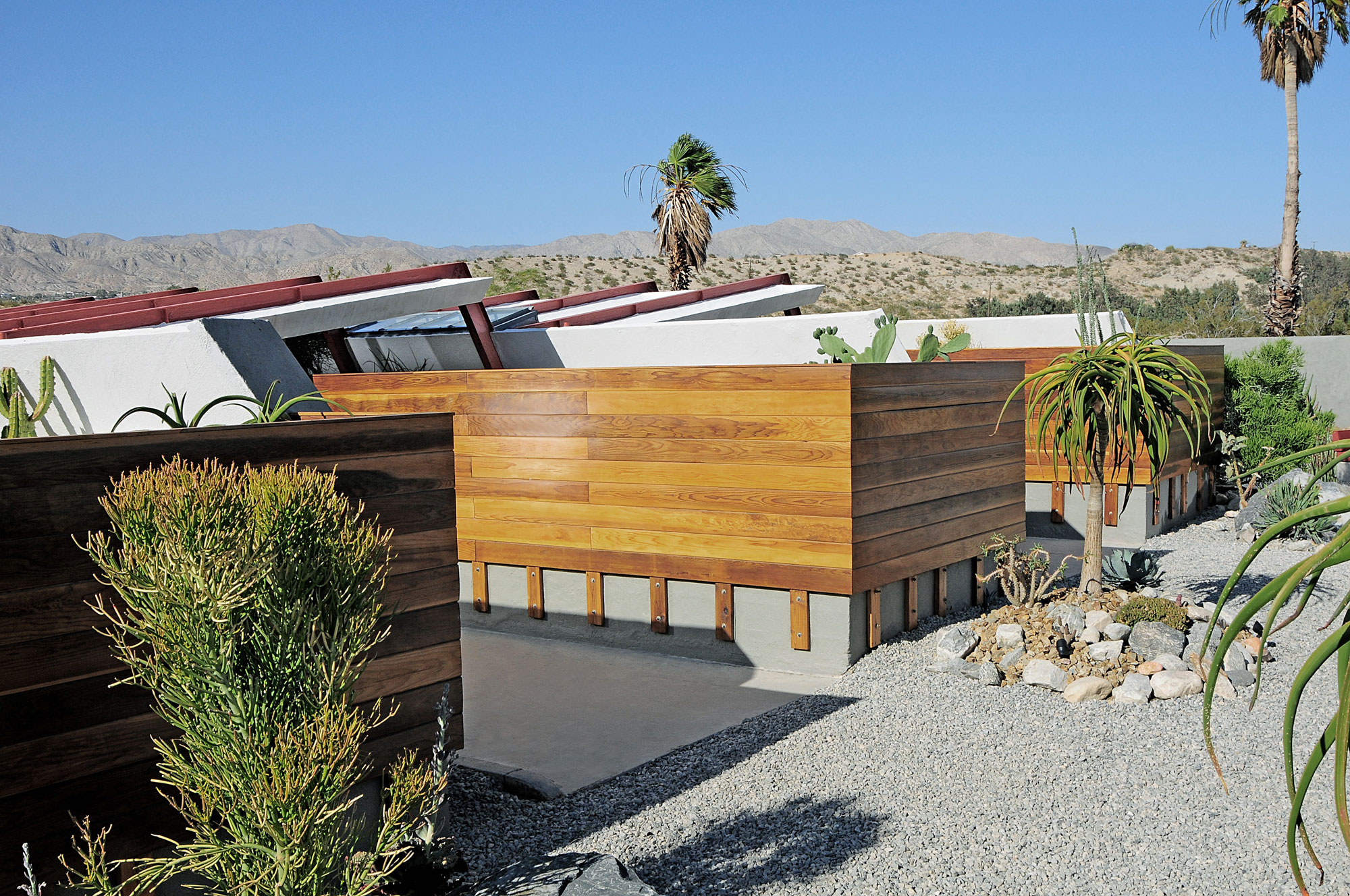 wood clad ranch style homes connected in a desert landscape and gravel drive