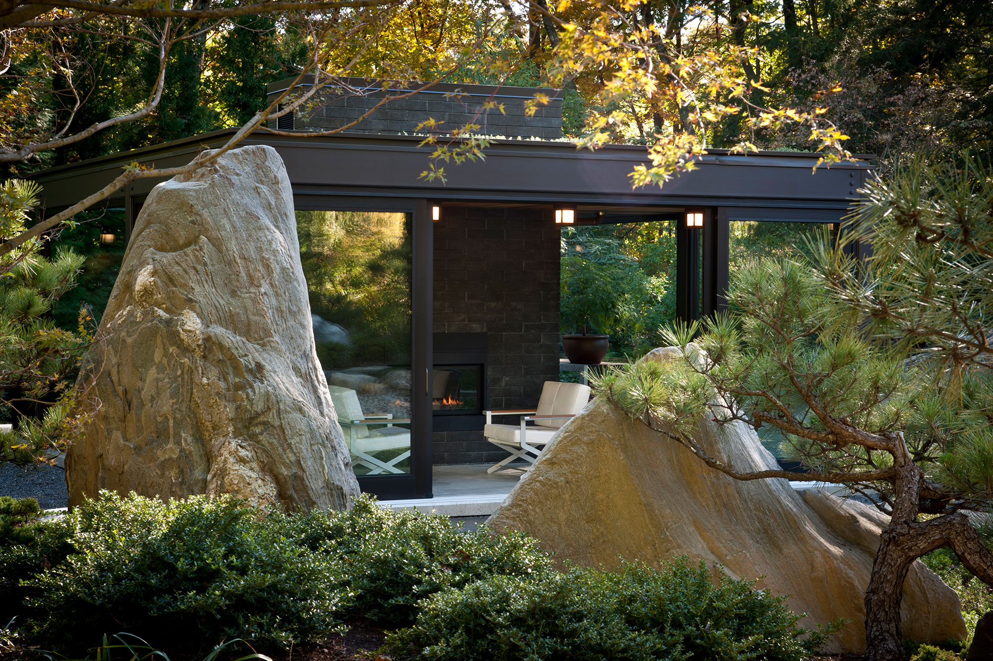 large boulder ledge in foreground with glass and steel greenhouse in background