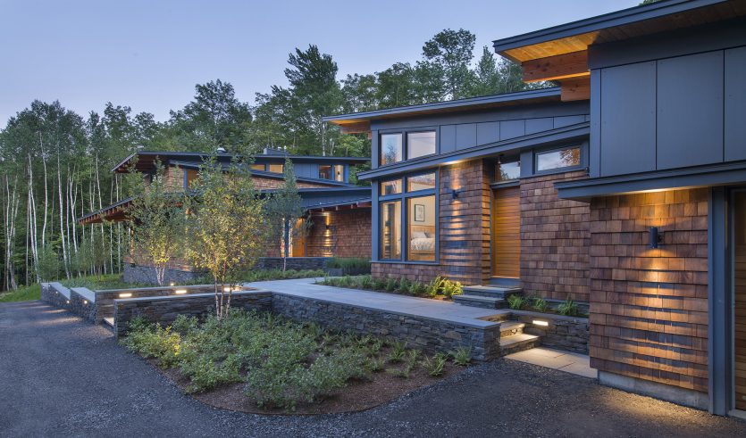 shed roof home with cedar shingles lit at dusk