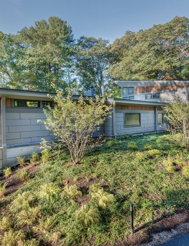 modern home with concrete retaining wall bermed into the landscape
