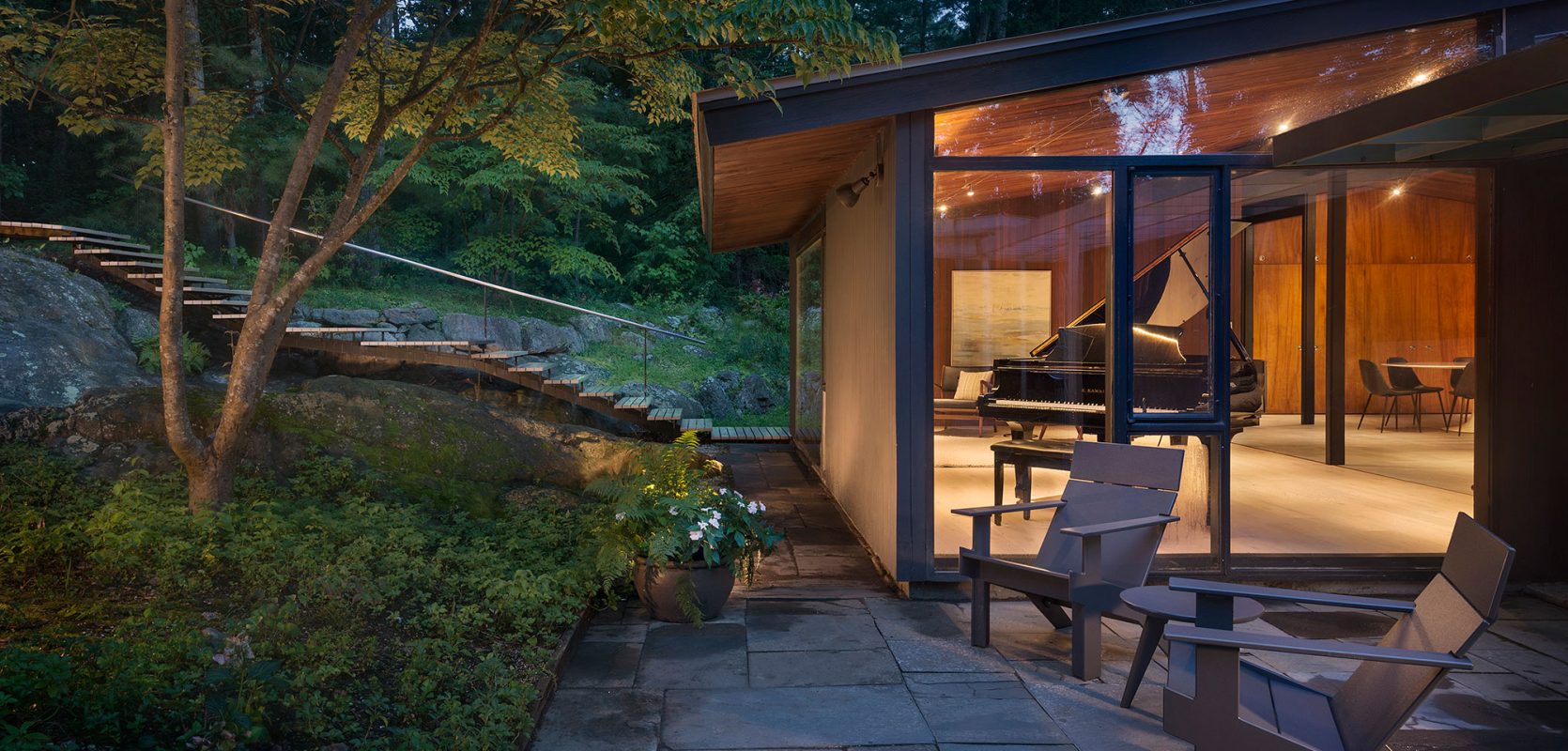 exterior of mid-century modern glowing at dusk grand piano