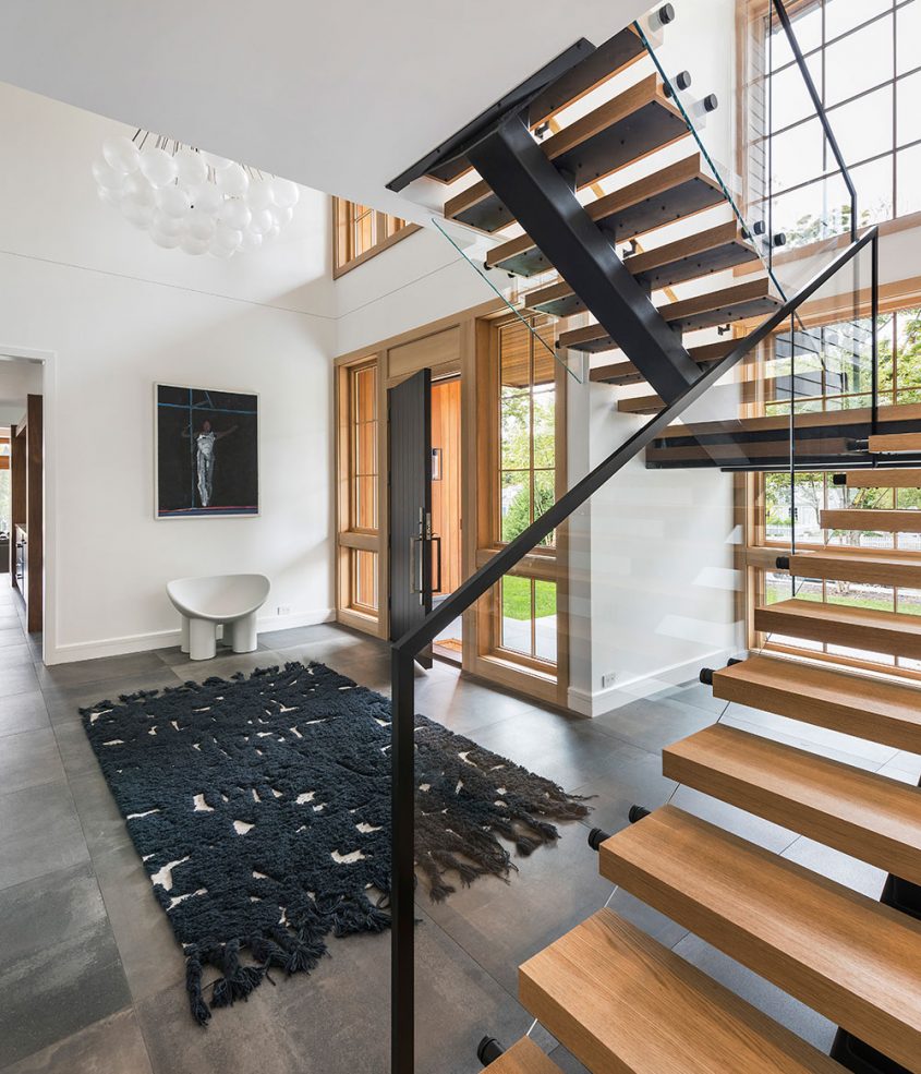 custom wood steel and glass staircase in cathedral ceiling foyer