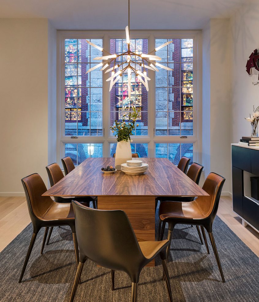 dining room with modern chandelier and church stained glass through the windows