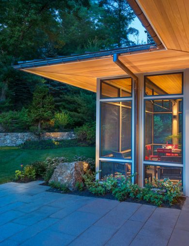 exterior corner of screen porch with extended wood soffits lit up at dusk