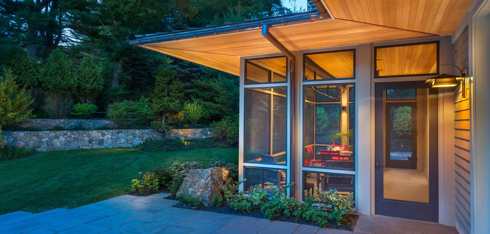 exterior corner of screen porch with extended wood soffits lit up at dusk