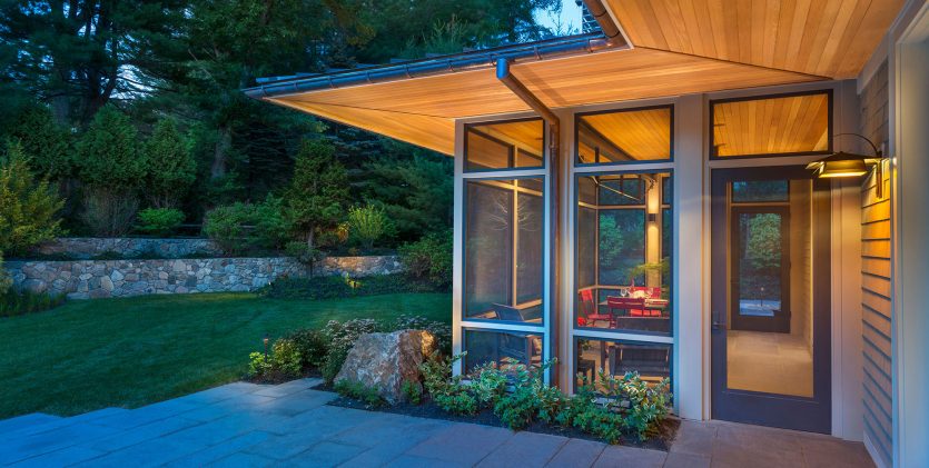 exterior corner of screen porch with extended wood soffits lit up at dusk