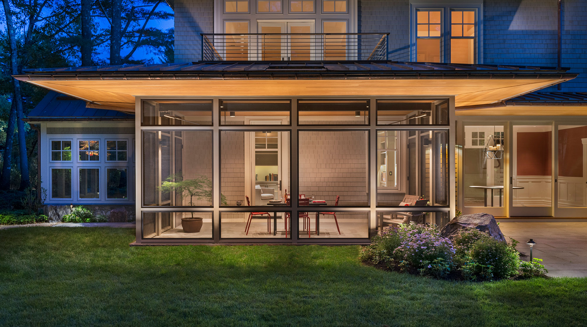 exterior of screen porch with extended wood soffits lit up at dusk