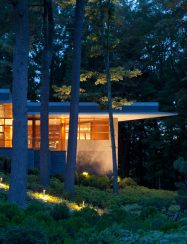 exterior corner of home glowing at night in the woods