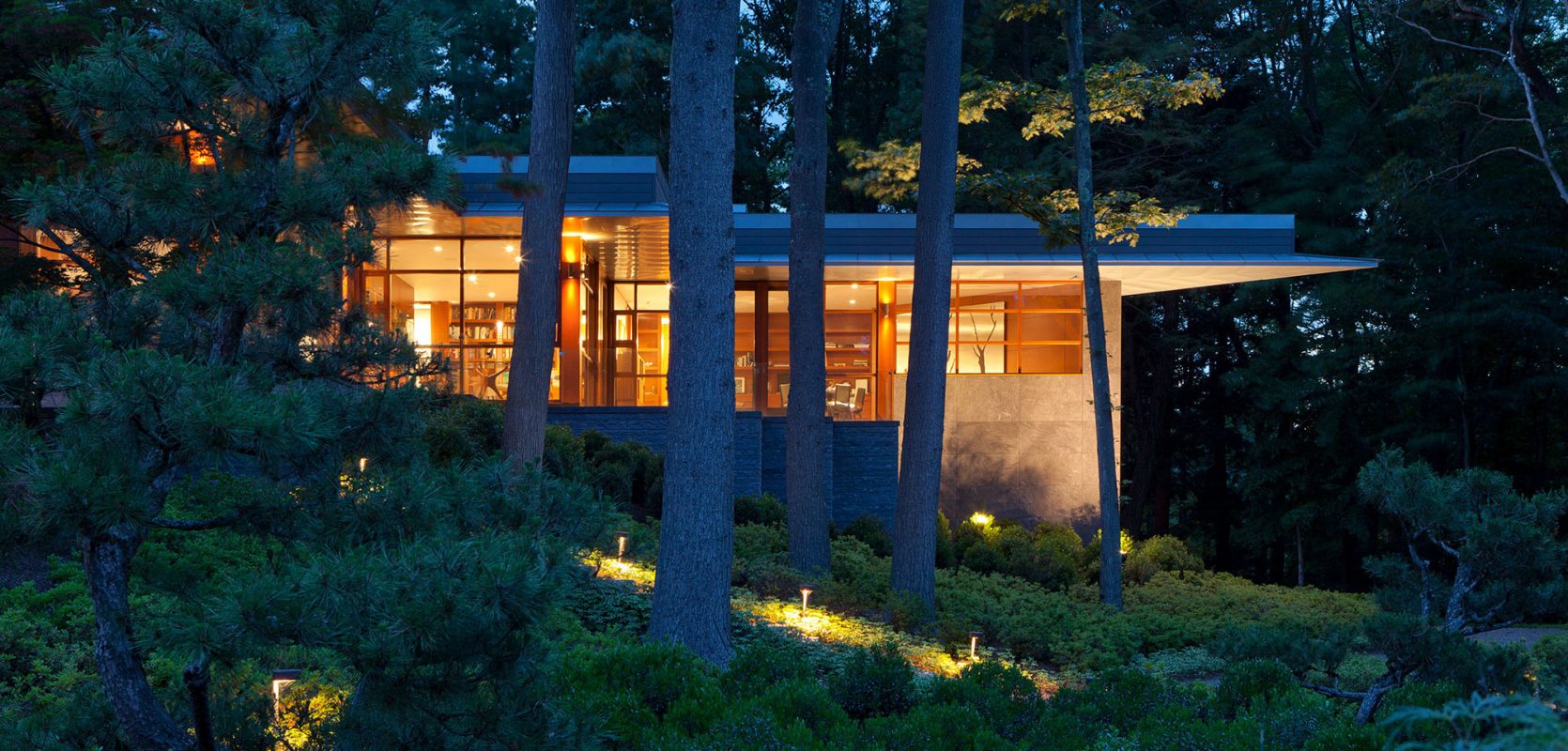 exterior corner of home glowing at night in the woods