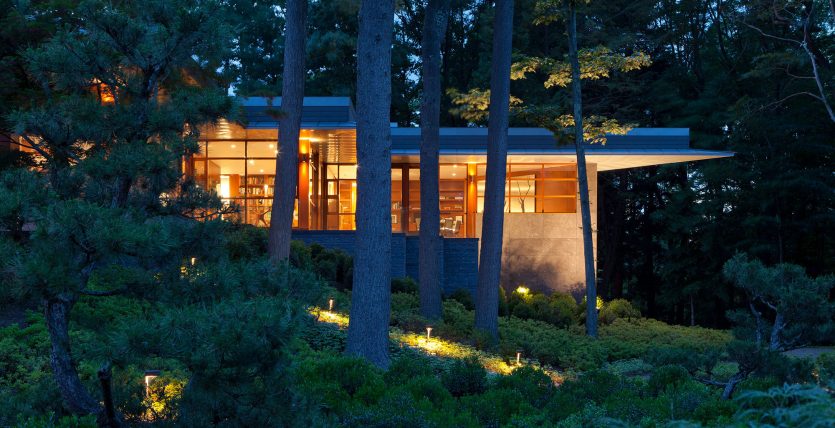 exterior corner of home glowing at night in the woods