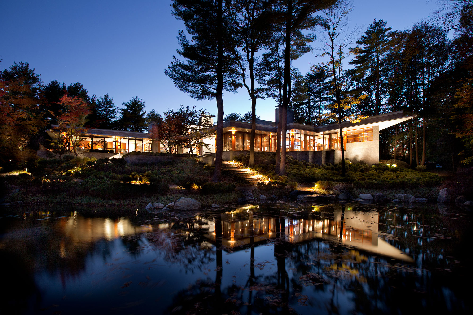 exterior of home across from a pond glowing at dusk