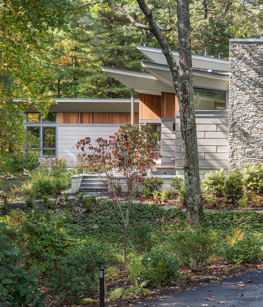 exterior of home with vertical cedar accents and warm grey metal siding and large stone chimney