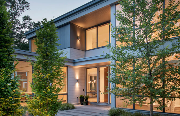 Evening lit front entrance with young trees and guiding walkway to home entrance.