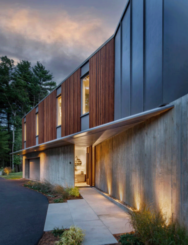 Evening image with contemporary lighting of front driveway and hidden entrance to home interior.