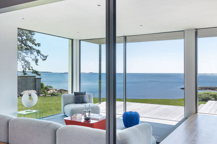 Conversation pit in modern open-plan living room with floor-to-ceiling glass showing ocean view of North Shore, Massachusetts
