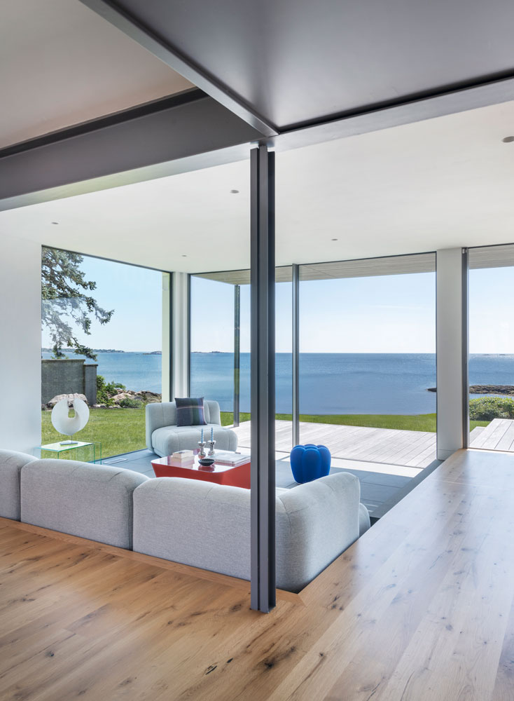 Conversation pit in modern open-plan living room with floor-to-ceiling glass showing ocean view of North Shore, Massachusetts
