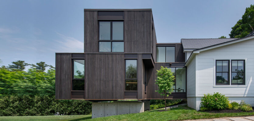 Front view of house addition by Flavin Architects. Wood details and beautiful floating addition with concrete base.