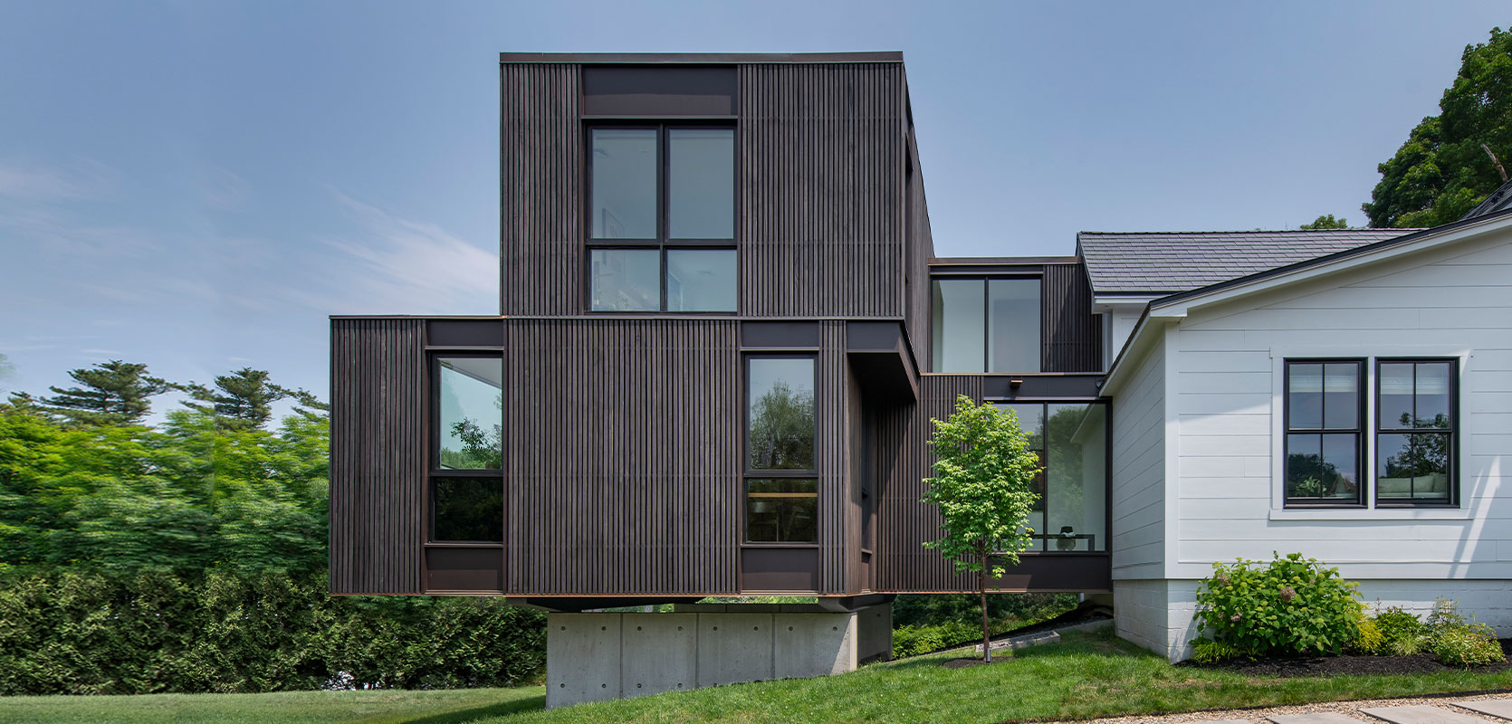 Front view of house addition by Flavin Architects. Wood details and beautiful floating addition with concrete base.