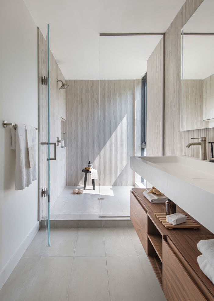 Contemporary bathroom with natural lighting. White tiling and open space for comfortable living.